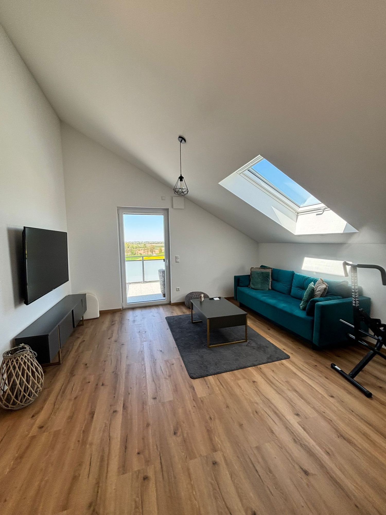 Fertiges Dachgeschoss: Wohnraum mit Dachfenster, Balkontür und Holzboden